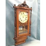 A Victorian walnut cased wallclock, with carved pediment above a rectangular crossbanded glazed door