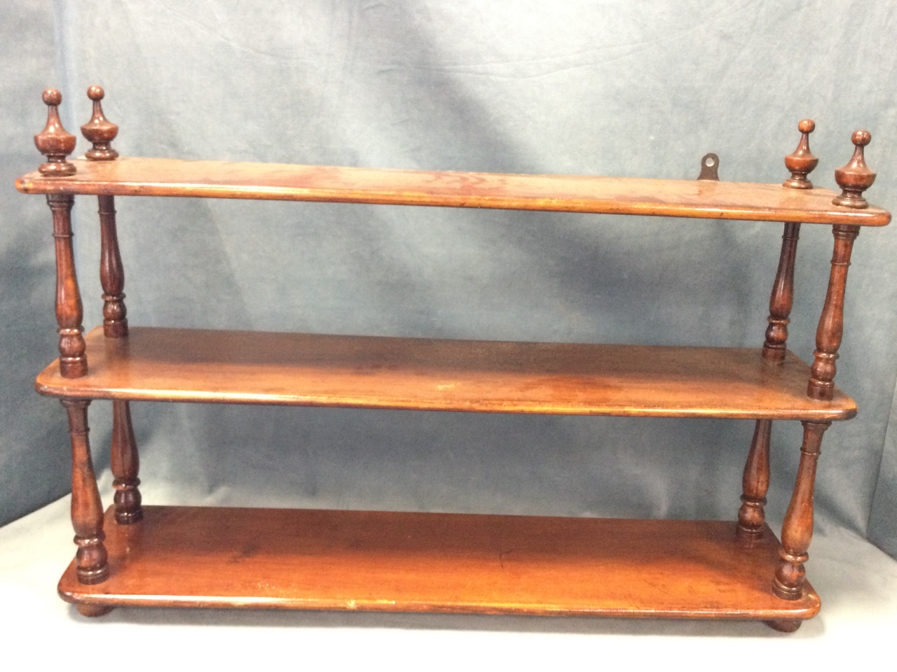 A set of nineteenth century stained wall shelves with three rounded platforms supported by turned