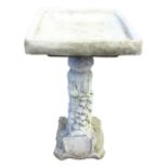 A composition stone garden birdbath, the square moulded bowl on ivy cast fluted column with