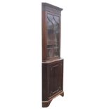 A Georgian style mahogany corner cabinet with moulded cornice above a fluted frieze having arched