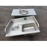 A circular stainless steel sink, the bowl with mixer tap set into a worktop; and a commercial