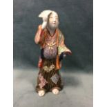 A 20th Century Japanese porcelain figurine modelled as cloaked gentleman holding fan, with