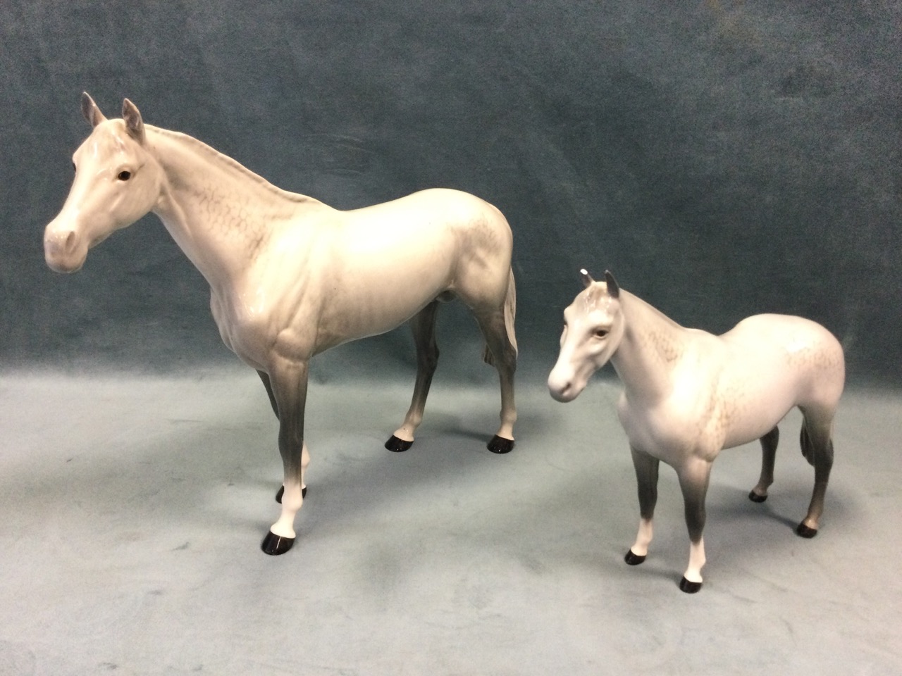 A graduated pair of Beswick dappled grey horses. (11in & 8in) (2)