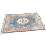 A Chinese thick-pile wool rug woven with oval floral medallion on pale blue field framed by pastel