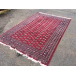 An Afghan wool rug woven in the Tekke style with rectangular field of oval and hooked medallions