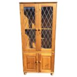 A pine glazed dresser cabinet with leaded glass doors enclosing shelves, above a fielded panelled