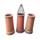 A set of three terracotta tubular tapering chimney pots with moulded rims and angled plinths - one