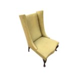 An Edwardian upholstered wing chair, the padded back and sides above a serpentine fronted sprung