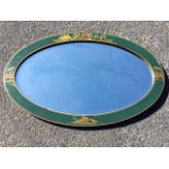 An oval lacquer framed mirror, the bevelled plate in green border framed by gilt bands, decorated