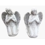 A pair of composition stone angels, the kneeling cloaked winged figures on plinths. (22in) (2)