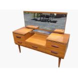A mid-century dressing table with rectangular mirror above a well with glass shelf, the cabinet with
