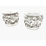 A pair of composition stone circular garden tubs, with shaped moulded rims above embossed friezes of