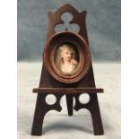 An oval painted porcelain miniature of a veiled lady in moulded mahogany frame on pierced easel