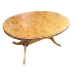 An oval pine Ducal dining table, the extending top with spare leaf, raised on twin-turned columns