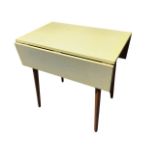 A formica topped beech drop-leaf table, the rectangular hinged top raised on tapering legs. (30in