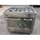 A Baumatic stainless steel range cooker with five burner gas hob, and electric oven with separate