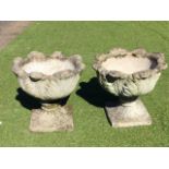 A pair of composition stone garden urns with circular leaf cast bowls on squat columns moulded