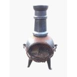 A cast iron chiminea garden patio stove with tubular chimney above bulbous burning chamber mounted