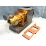 A tin case magic lantern projector, the box with leather handle housing a projector with brass