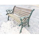 A cast iron garden bench with slatted back & seat, having scrolled arms on channelled sabre legs -