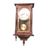 A reproduction mahogany Vienna style wallclock, the arched door framed by turned columns enclosing