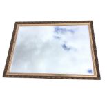 A large reproduction gilt framed mirror with rectangular bevelled plate in foliate scrolled