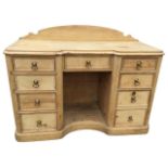 A Victorian pine kneehole dressing table with arched back above a breakfront moulded top, having