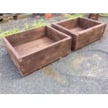 A pair of wood garden planters, the boxes formed from thick scaffolding boards, raised on