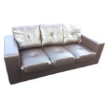 A contemporary faux leather three-seater sofa with loose cushions and rectangular padded platform