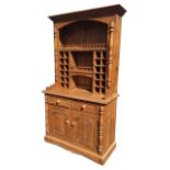 A pine kitchen dresser with moulded cornice above an arched apron and wide shelf bordered by