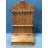 A nineteenth century oak spoon rack, the shaped back with two battons of holders above a candlebox