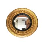 A circular regency style mirror with convex plate in fluted ebonised border, the giltwood moulded