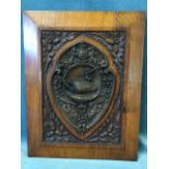 A nineteenth century oak panel carved with oak leaves and acorns, mounted with a bronze shield