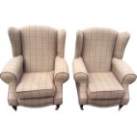 A pair of contemporary upholstered wing armchairs with loose cushions and brass studding to the