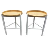 A pair of circular Ercol coffee tables, the tray tops on three painted skittle-tuned legs joined