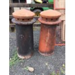 A pair of tubular tapering terracotta chimney pots with pierced domed covers. (28.5in) (2)