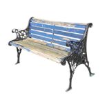 A cast iron garden bench with slatted back & seat, the scrolled arms on pierced flowerhead