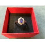 A boxed tanzanite and multi-gem ring, the claw set central blue tanzanite surrounded by a shield