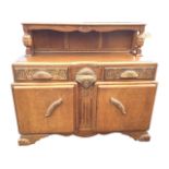 A 1950s carved oak sideboard, the panelled back with shelf on bollection turned columns, the base