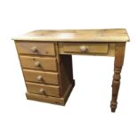 A reproduction pine desk with rectangular top raised on baluster turned legs, with kneehole