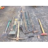 Miscellaneous hand tools including a long-reach branch loper, forks, hoes, a pick axe, a log