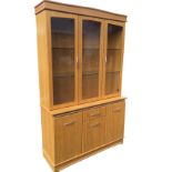 A modern oak display cabinet, the top with three glazed doors with bevel cut decoration enclosing