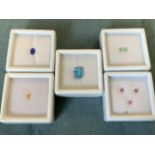 Five boxed/cased loose stones - an electric blue octagon cut topaz - 3.6 carats, an oval blue spinel