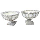 A pair of composition stone garden urns with circular leaf cast bowls on squat fluted columns and