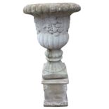 A large composition stone garden urn with lobbed rim above a frieze cast with fruit on a fluted body