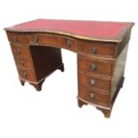 A serpentine fronted mahogany kneehole desk with skiver to moulded top, having central concave