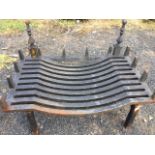 A cast iron dog grate with rectangular curved burning platform framed by tapering pillars, supported
