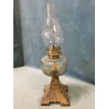 A late Victorian cast iron oil lamp with decorative gilded leaf embossed base beneath a bun shaped
