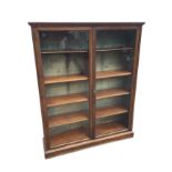 A glazed Edwardian mahogany bookcase, formerly a gun cupboard with baize lining, having dentil