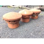 A set of three terracotta vented chimneypot cappings with mound tops on tubular bases. (11in x 8.